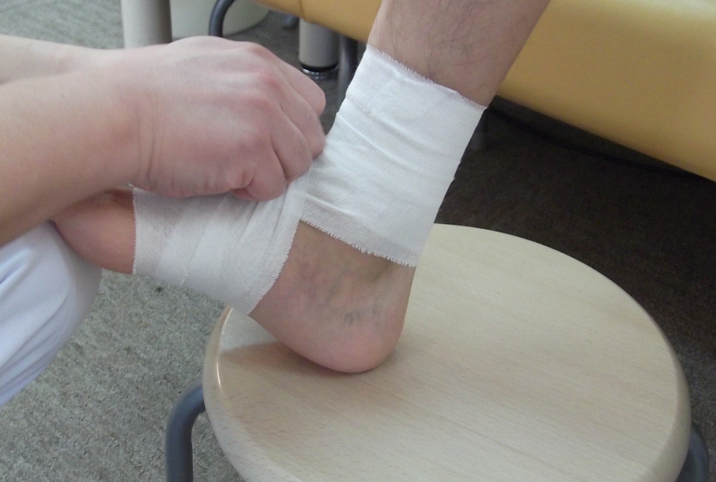 足関節の固定処置として足首に包帯を巻く、くめ鍼灸整骨院の施術風景