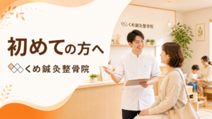 くめ鍼灸整骨院の院内で、白衣のスタッフが椅子に座る女性患者へ説明している「初めての方へ」案内バナー